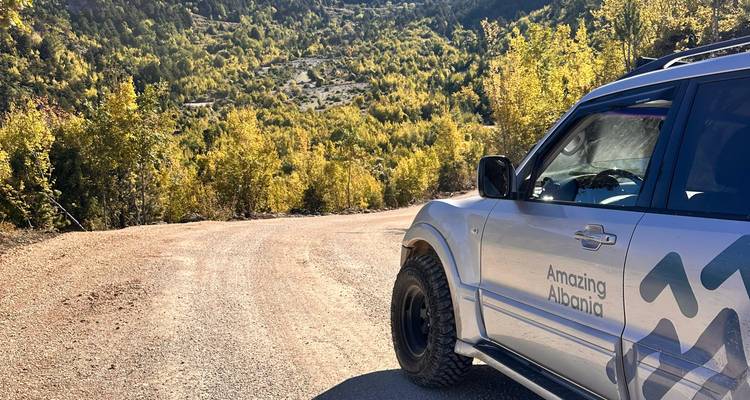 SUV en un camino de tierra con colinas boscosas de fondo