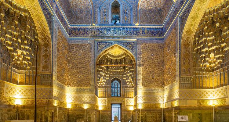 Interior de una gran mezquita ornamentada con patrones intrincados.