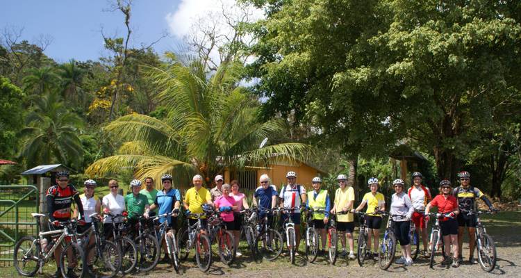 Grand groupe de cyclistes posant pour une photo dans un cadre forestier.