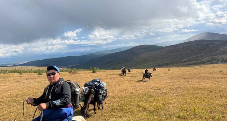 Una persona liderando un grupo de jinetes en un paisaje abierto.