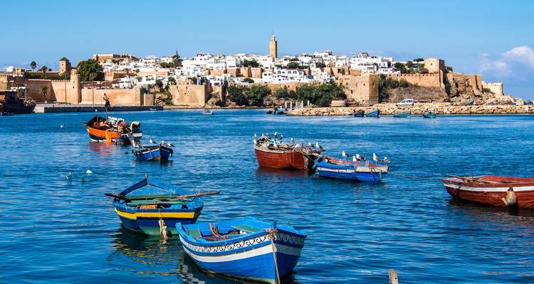 Des bateaux colorés dans l'eau avec une ville en arrière-plan.