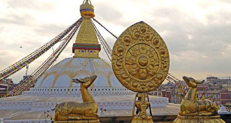 Un stupa avec des statues de cerfs dorés devant sous un ciel nuageux.