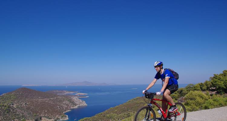 L'homme fait du vélo avec une vue sur la mer et les montagnes.
