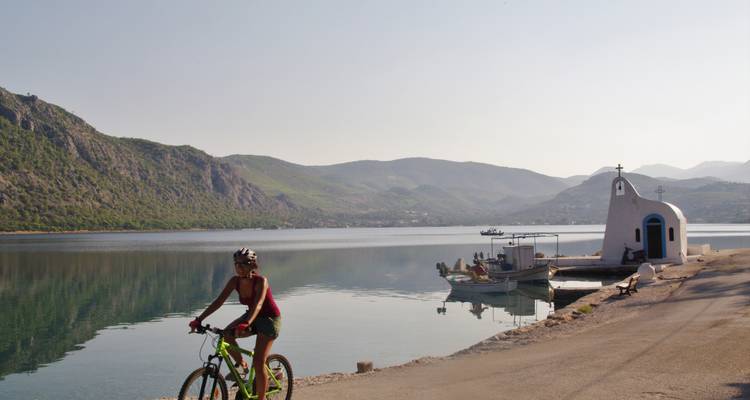 Cycliste passant devant une petite chapelle près de la mer.