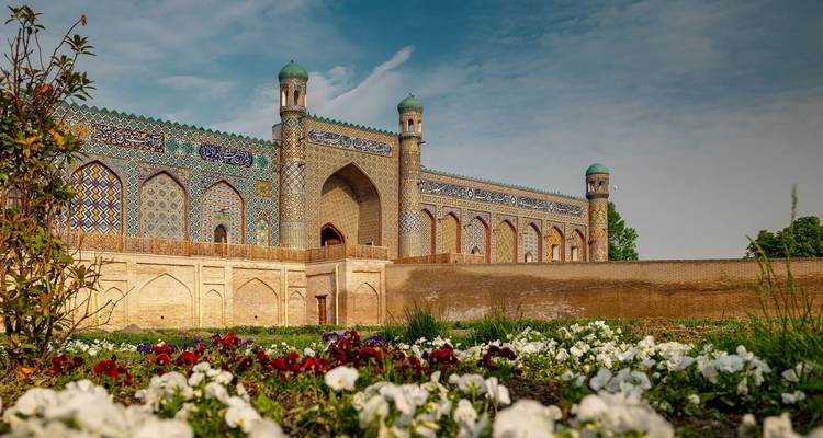 Historisches Gebäude mit bunter Kachelfassade, umgeben von Blumen.