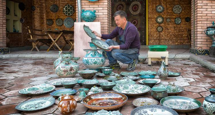 Potter, der blaue Töpferwaren in einer Werkstatt betrachtet.