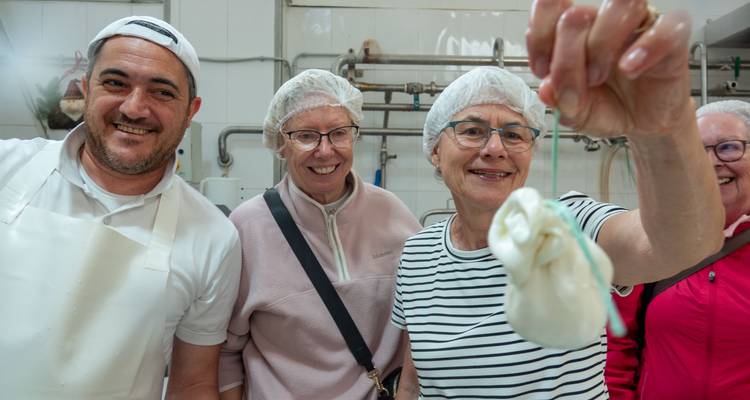 Le fromager présente avec fierté de la mozzarella fraîche aux visiteurs souriants à l'intérieur d'une laiterie.