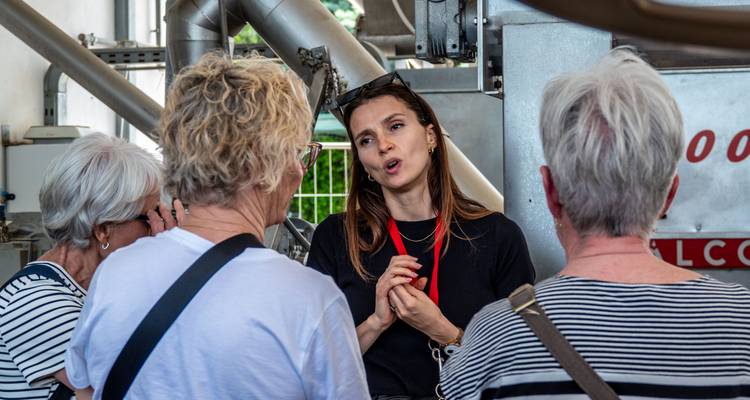 Le guide explique les machines à l'intérieur d'une installation de production d'huile d'olive à des visiteurs intéressés.