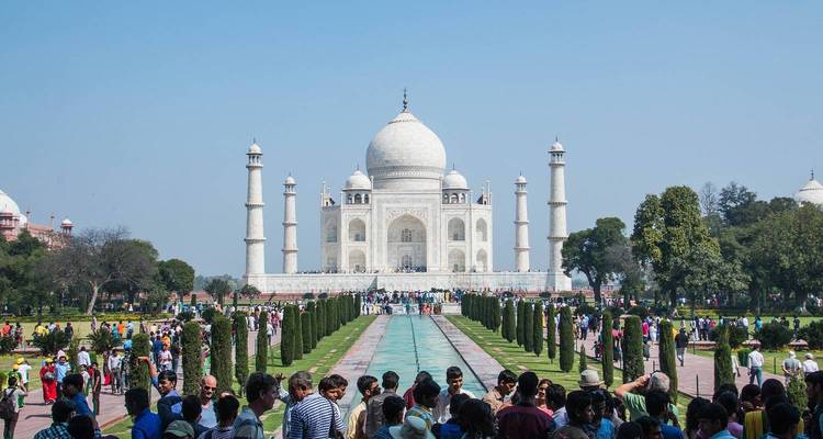 El Taj Mahal con jardines y visitantes en primer plano.