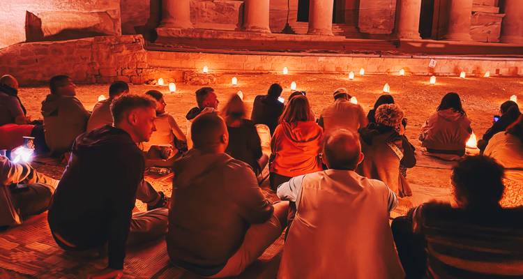 Besucher sitzen während Petra by Night im Innenhof des antiken Schatzhauses stillschweigend bei Kerzenlicht.