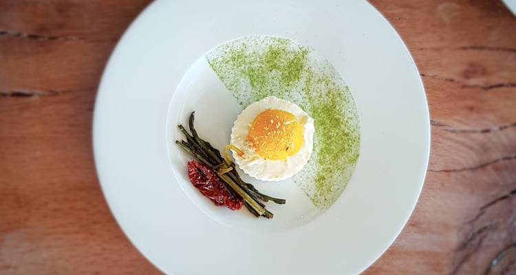 Plato gourmet con huevo, verduras y guarnición en un plato.