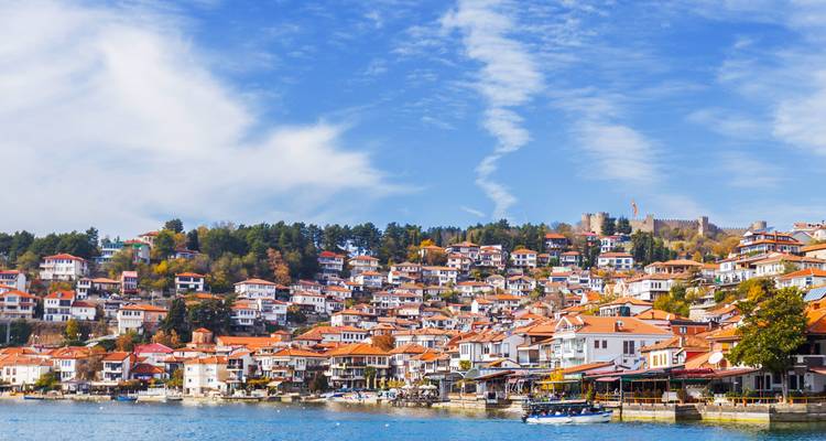 Vista panorámica de un pueblo junto al lago con tejados de tejas rojas.