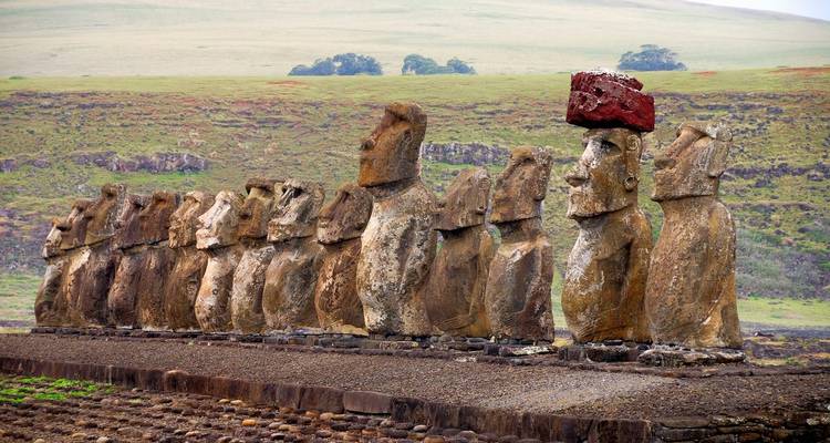 Alignement de statues Moaï sur une plaine herbeuse.