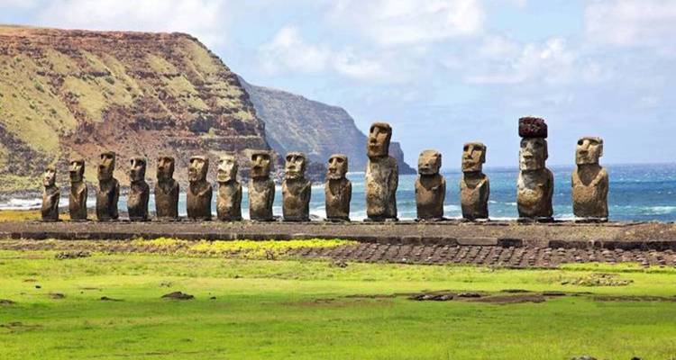 Rangée de statues Moaï avec un arrière-plan de falaises maritimes.