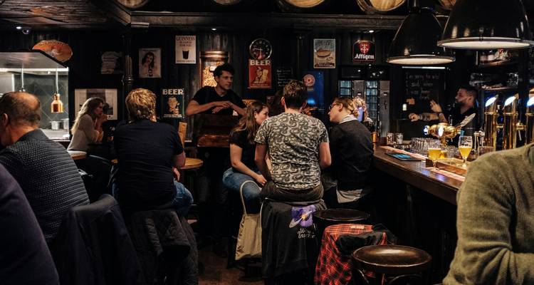 Interior de un pub acogedor con gente socializando y bebiendo.