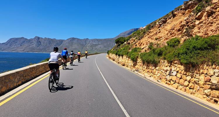 Des cyclistes roulant le long d'une route côtière avec des vues spectaculaires sur les montagnes et l'océan.