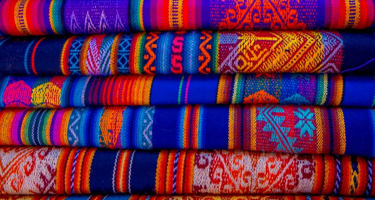Colorful handwoven textiles stacked.