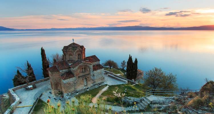 L'église en pierre de Saint-Jean à Kaneo perchée au-dessus des eaux calmes du lac d'Ohrid au coucher du soleil.