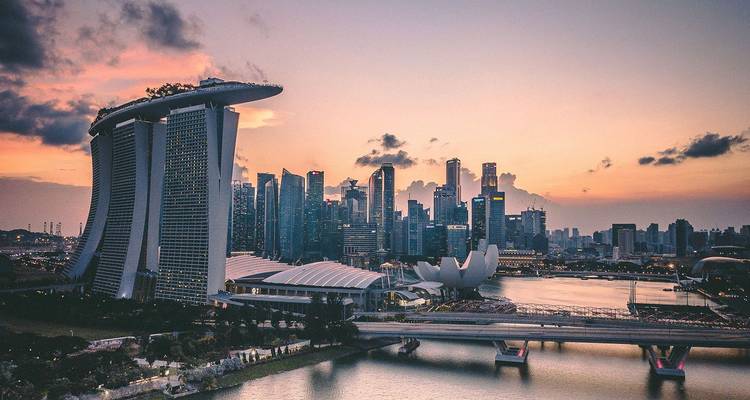 El horizonte de Singapur al atardecer mostrando Marina Bay Sands y el Museo ArtScience reflejados en la bahía.