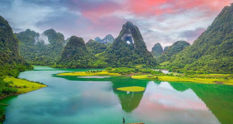 Paisaje sereno de agua con pequeñas islas y formaciones montañosas distintivas.