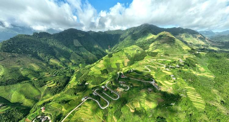 Vista aérea panorámica de una carretera serpenteante a través de montañas verdes.