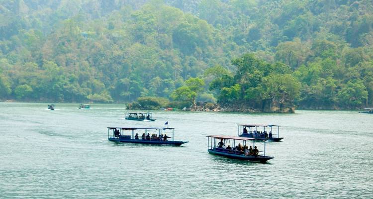 Barcos en un río ancho rodeado de bosques densos y cielos despejados.