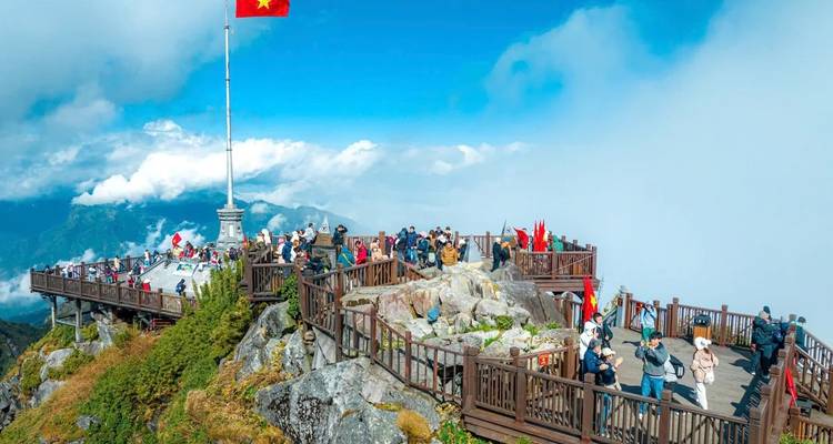 Turistas en una cubierta de montaña with la bandera de Vietnam en el fondo.