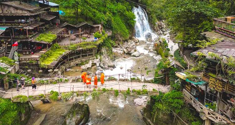 Turistas caminando en un puente de madera cerca de una cascada.