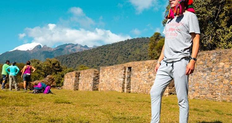 Hombre posando con ruinas y montañas al fondo.