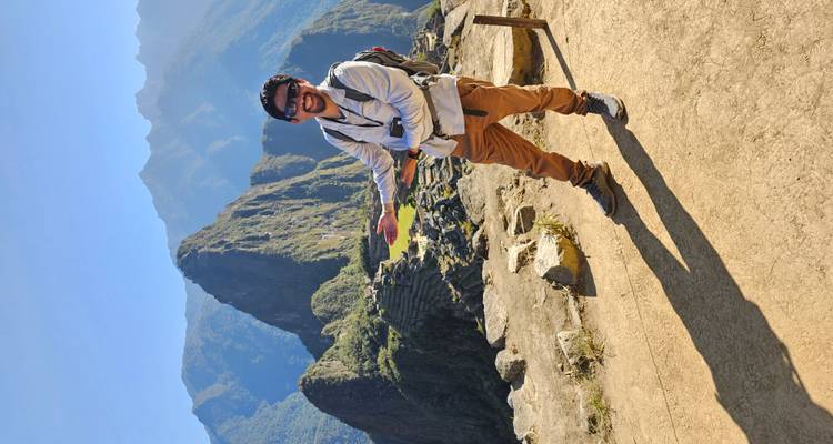 Persona sonriendo y posando con Machu Picchu detrás.
