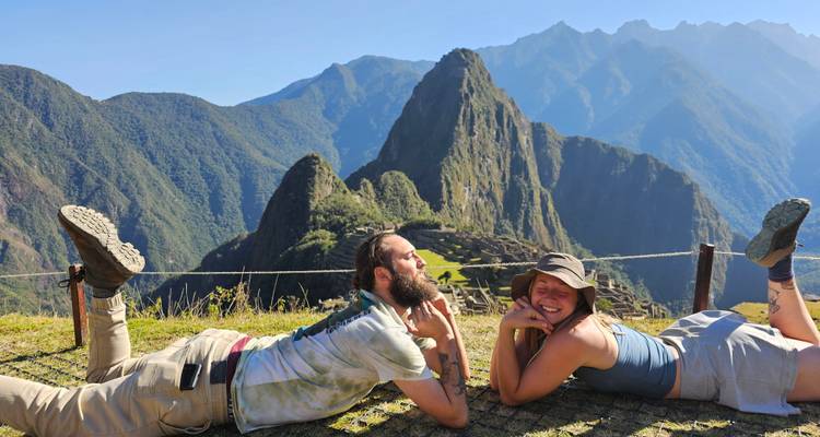Dos personas posando juguetonamente con Machu Picchu de fondo.