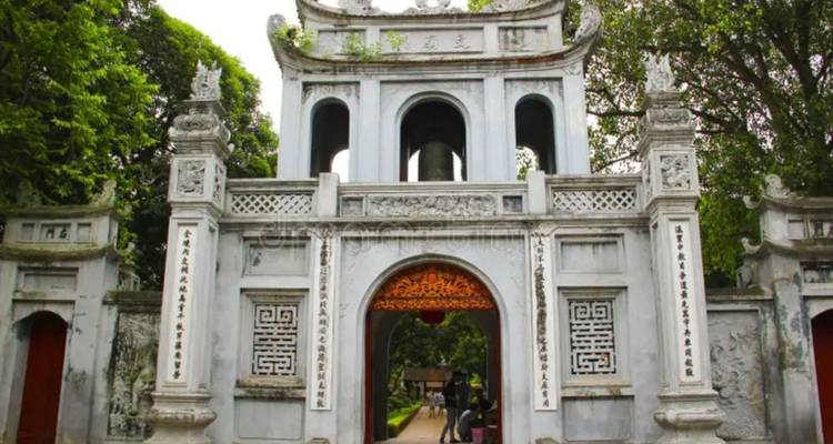 Grey stone entrance gate of the Temple of Literature surrounded by lush trees.