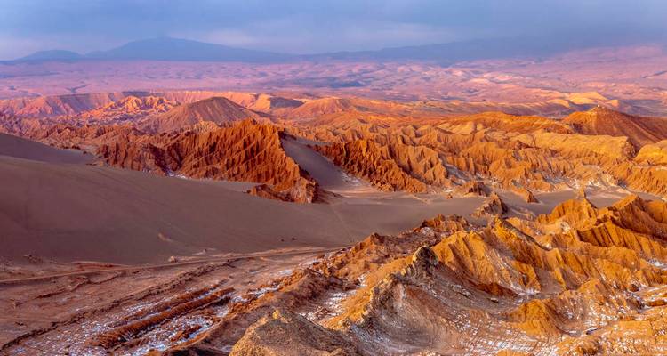 Eroded desert landscape under a colorful sky.