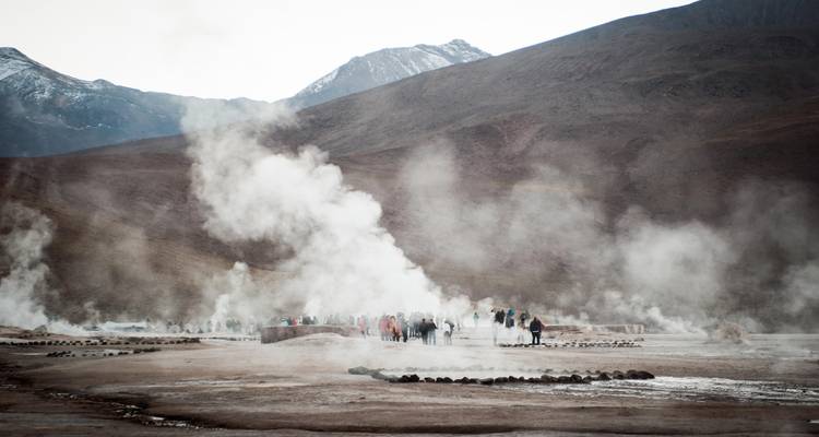 Group of people walking through steam in a geothermal area.