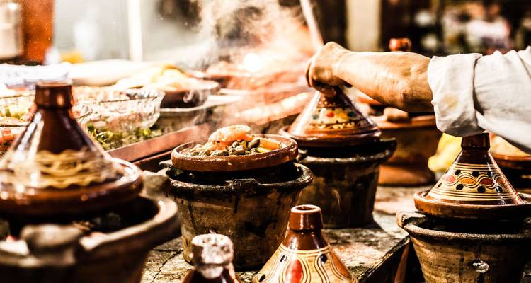 Cocina tradicional marroquí en tagine en un ambiente de mercado.