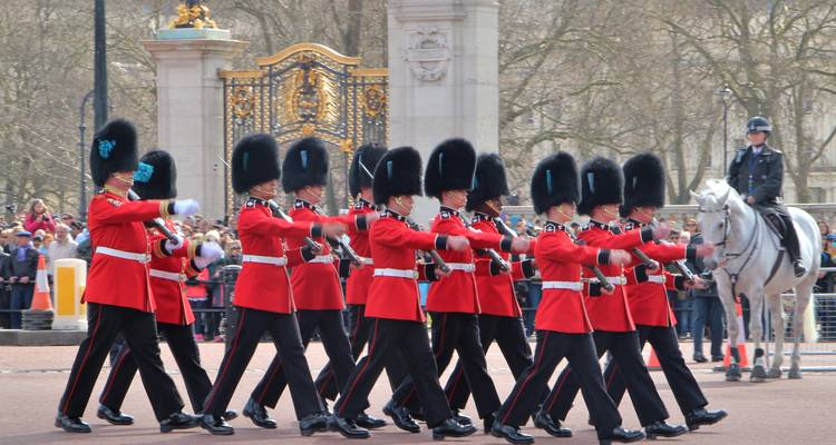 Changing of the Guard ceremony with soldiers in red uniforms marching outside palace gates