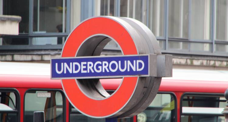 Close-up of iconic London Underground roundel sign with red bus blurred behind
