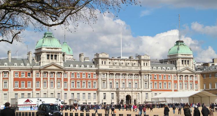 Horse Guards Parade and Old Admiralty Building with red-brick façade and green domes bustling with visitors under blue skies.