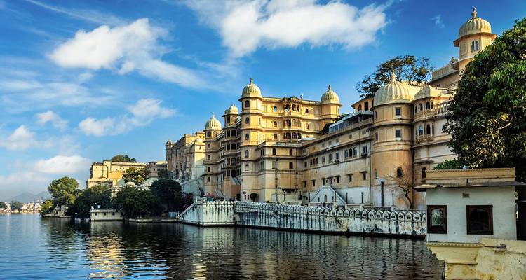 City Palace of Udaipur stretching along Lake Pichola under a bright blue sky.