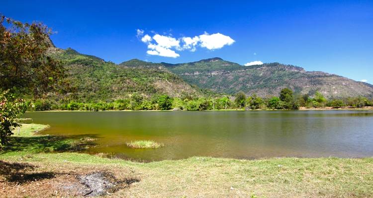 Lago sereno con fondo montañoso bajo un cielo azul brillante.