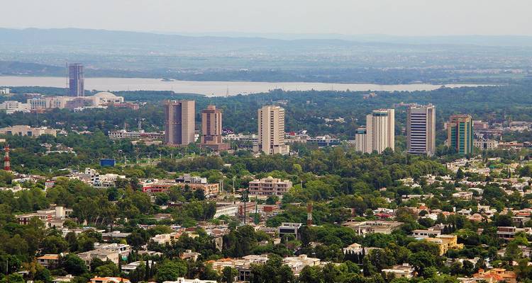 Panoramic view of Islamabad city skyline surrounded by green trees with mountains in background