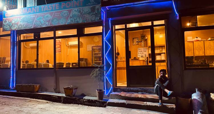 Eine Person, die nachts vor einem Restaurant sitzt.