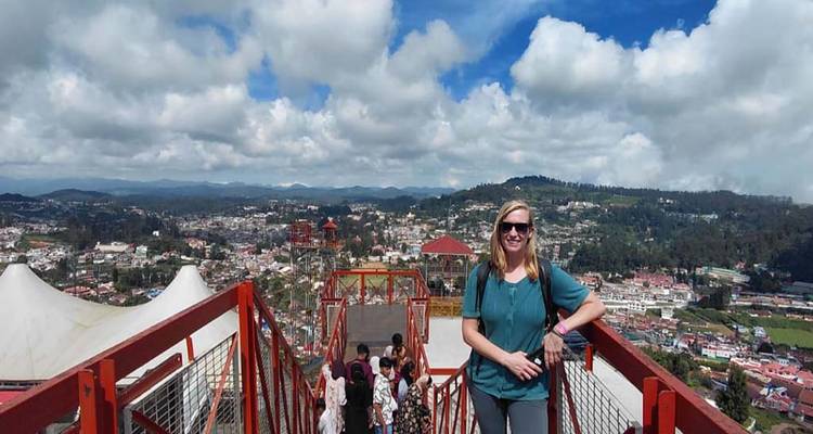 Person posing at a viewpoint overlooking a city.