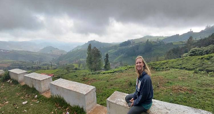 Individual sitting on a wall with views of hills.