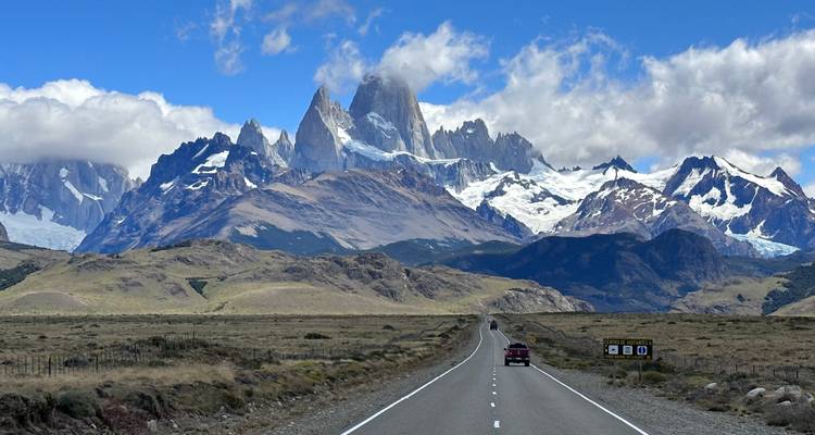 Un largo camino recto que lleva hacia los dramáticos picos nevados del macizo del Monte Fitz Roy