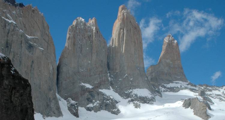 Iconic granite towers of Torres del Paine rising steeply above snowfields.