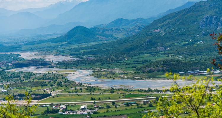 Vast valley landscape with braided river channels and distant mountain ridges.