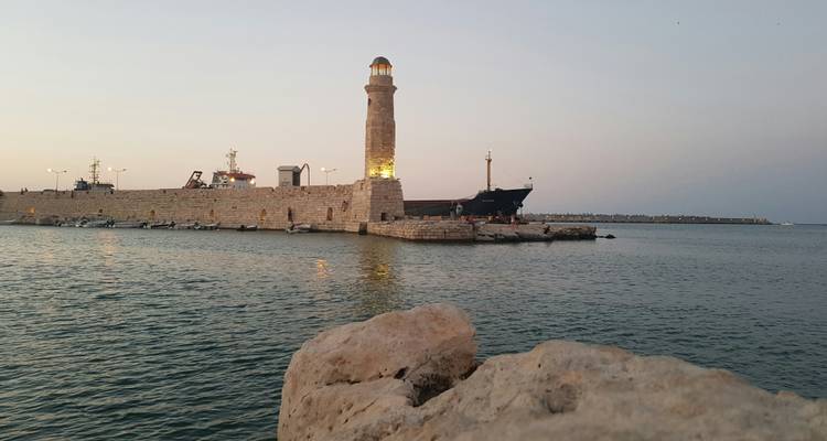Vue en soirée du phare du port de Rethymnon illuminé avec des eaux marines calmes