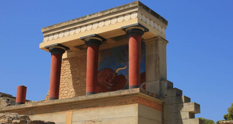 Piliers rouges restaurés et fresque au Palais de Knossos sur un ciel bleu dégagé