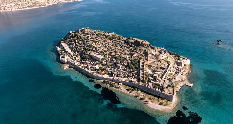 Vue aérienne par drone de l'île fortifiée de Spinalonga entourée par une mer turquoise cristalline au large de la côte de la Crète.
